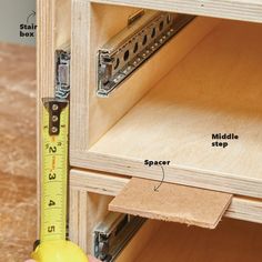 a person measuring the width of a drawer with a tape measure and wooden drawers in front of them