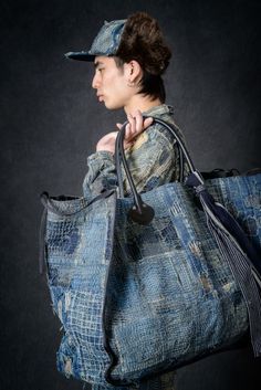 a woman carrying a large blue tote bag on her shoulder and wearing a baseball cap