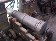 an old cannon is on the deck of a large wooden sailing ship with roped ropes