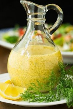 a glass pitcher filled with liquid sitting on top of a plate next to a lemon wedge