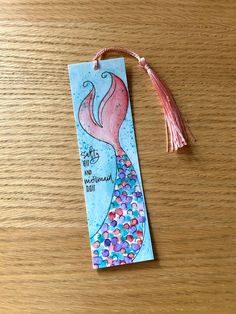 a bookmark with an image of a mermaid on it and a tassel attached to it