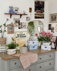 a dresser with flowers and pictures on the wall