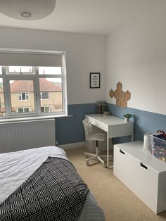 a bedroom with a bed, desk and dresser next to a window in the room