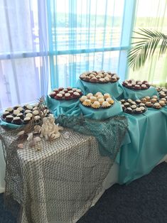 a table topped with lots of desserts on top of a blue cloth covered table