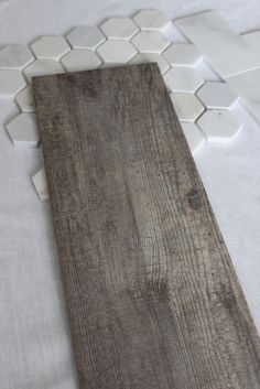 a wooden plank laying on top of a white tile floor with hexagonal tiles in the background