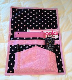 a pink and black polka dot blanket with a remote control in the pocket next to it