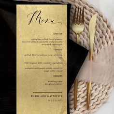 a menu card with gold foil on it next to a fork and knife in a woven basket