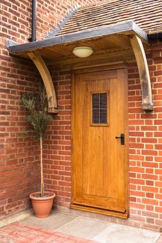 a potted plant sitting in front of a wooden door on a brick wall next to a doorway