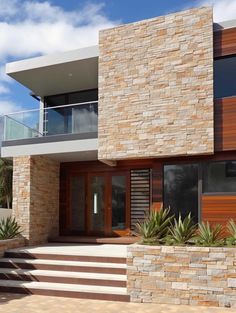 a modern house with stone and wood sidings on the front door, stairs leading up to the second floor