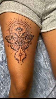 a woman's thigh with a moth tattoo on her leg and the sun above it