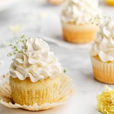 several cupcakes with white frosting and flowers on them sitting on a table