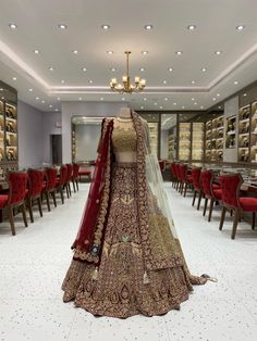 a bride's wedding dress is displayed in the middle of a room with red chairs