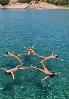 four people floating in the water with their arms around each other while doing acrobatic tricks