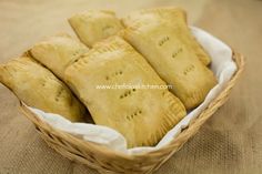 several pastries in a wicker basket sitting on a brown tableclothed surface