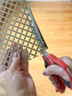 a person cutting paper with scissors on a wooden floor next to a hard wood floor