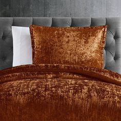 a bed with two pillows on top of it and a brown comforter in the middle