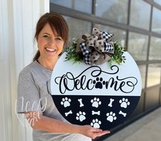 a woman holding up a welcome sign with dog paw prints and a bow on it