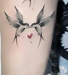 a couple of birds flying next to each other on a woman's leg with a heart in the middle