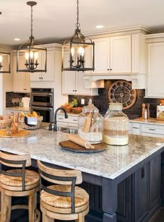 a large kitchen island with stools and lights hanging from it's ceiling above it