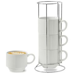 a white coffee cup sitting next to a stack of mugs on a metal stand