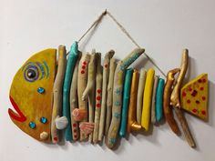 a fish made out of wooden sticks hanging from a string on a white wall with other items attached to it