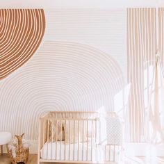 a baby's room with a white crib in the center and a large wall mural behind it