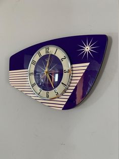 a blue clock mounted to the side of a wall next to a white wall with a star on it