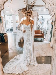 a woman is standing in front of a mirror wearing a wedding dress with feathers on it