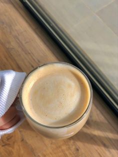 a person holding a cup of coffee on top of a wooden table