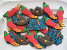 decorated cookies in the shape of cowboy boots and chili peppers on a white platter