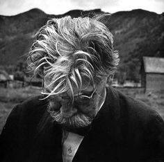 black and white photograph of an old man with glasses looking at something in the distance