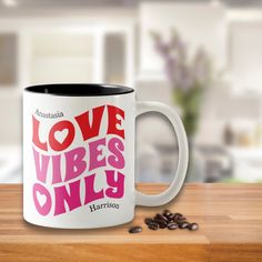 a coffee mug with the words love vibes only on it next to some coffee beans