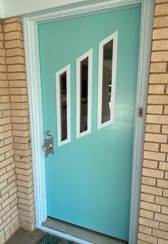 a blue front door with three windows and a rug on the ground in front of it