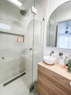 a bathroom with a glass shower door, sink and mirror on the wall next to it