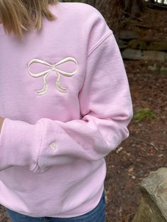 Get cozy and stylish with our Big Bow Sweatshirt! This adorable, girly sweatshirt features a cute bow design, perfect for adding a touch of style to any outfit. The sleeve has a tiny heart design on the sleeve for an extra custom touch.  Whether you're out for a stroll or lounging at home, this sweatshirt is sure to keep you looking chic and feeling comfortable. Perfect for gifting to the fashionista in your life! A soft 50/50 sweatshirt (cotton and polyester) is machine embroidered with the des Casual Long Sleeve Bow Sweater, Casual Long Sleeve Sweater With Bow, Pink Sweatshirt For Loungewear, Sweet Long Sleeve Cotton Sweatshirt, Cute Long Sleeve Sweatshirt For Loungewear, Preppy Pink Tops For Fall, Preppy Long Sleeve Cotton Sweatshirt, Preppy Cotton Sweatshirt For Fall, Pink Bow Top For Fall