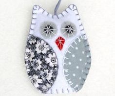 an owl ornament hanging from a string on a white surface with flowers and dots