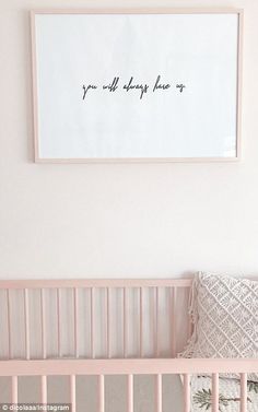 a pink crib with a framed quote above it