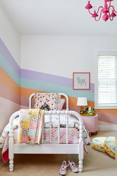 a white bed sitting in a bedroom next to a pink chandelier and window