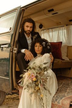 a man and woman sitting in the back of a truck with their arms around each other