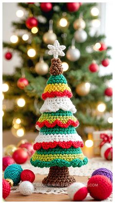 a crocheted christmas tree sitting on top of a table next to a christmas tree