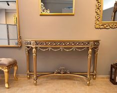 an ornate console table in the corner of a room with two mirrors on the wall