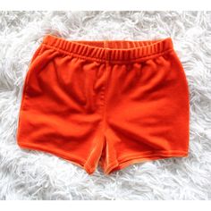 an orange shorts is laying on a fluffy white carpet and it looks like the bottom part of a child's pants