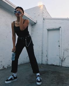 a woman in black jumpsuit holding a water bottle and cell phone