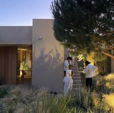 two people are standing in front of a house that has stairs leading up to it