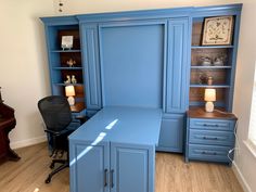 a blue desk and chair in a room with wooden floors, built - in bookshelves and cabinets