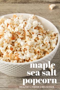 maple sea salt popcorn in a white bowl on a wooden table with text overlay that reads maple sea salt popcorn