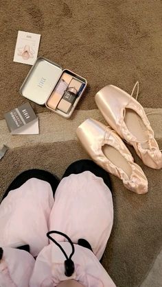 two pairs of ballet shoes are laying on the floor next to an open box of personal care products