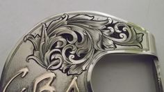 a silver belt buckle with arabic writing on the front and sides, decorated with an ornament