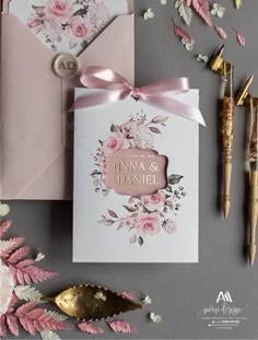 wedding stationery with pink flowers and gold foil on it, next to an envelope