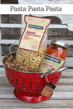 a red colander filled with pasta and sauces on top of a wooden table